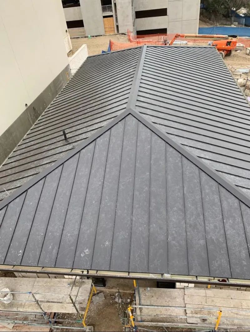Commercial metal roof construction with crane equipment in Bastrop